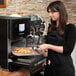 A woman in a black apron using a Merrychef eikon e1s countertop oven to cook a sandwich.