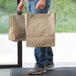 A man holding two Sabert 2 entree meal kraft paper bags.