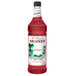 A Monin Premium Pineberry Flavoring Syrup bottle filled with red liquid.