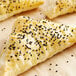A close up of a croissant with black caraway seeds.