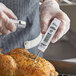 A person using a Choice digital pocket probe thermometer to measure the temperature of a cooked chicken.
