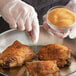 A person in gloves sprinkles Regal Roasted Garlic Granules on chicken.