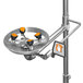 A polished chrome safety station with orange and black accents and a stainless steel shower head.