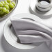 A white plate with a Snap Drape stone Milan birdseye cloth napkin and grapes on it.