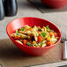 A red Sensation melamine bowl filled with pasta, vegetables, and basil.