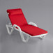 A white Lancaster Table & Seating chaise lounge with red cushion and pillow.