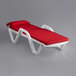 A white Lancaster Table & Seating chaise lounge with red cushions and pillow.