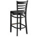 A Lancaster Table & Seating black wood ladder back bar stool with a black wood seat.