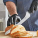 A person in gloves using a Schraf serrated bread knife to slice bread.