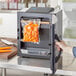A person using a VacPak-It vertical vacuum packaging machine to seal a bag of carrots.