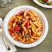 A white Ecopax polypropylene plate with pasta, vegetables, and sauce.