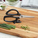 Mercer Culinary Japanese steel kitchen scissors on a cutting board with green onions.