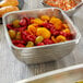 A Vollrath square metal serving bowl filled with yellow and red bell peppers on a wood table.