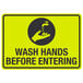 A yellow and black aluminum sign with the words "Wash Hands Before Entering" and a black and white symbol of a hand washing a faucet.