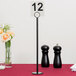 A black Tablecraft flat bottom menu holder with a number on it.