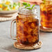 Two Acopa Rustic Charm mason jars filled with iced tea and ice.