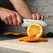 A person's hands using a Shun Classic Santoku knife to slice an orange.
