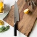 A Shun Classic chef knife on a cutting board with lemons and rosemary.