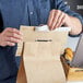 A person using a 13" handle cuff tamper evident seal on a brown paper bag.