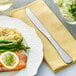 A table set with a plate of salmon, rice and asparagus with an Acopa Vernon stainless steel table knife.