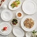 A white table with Acopa Condesa white porcelain cups of coffee and plates of food.