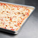 A rectangular pizza in an American Metalcraft square deep dish pizza pan on a table.