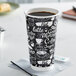 A black and white Choice Coffee Break paper hot cup filled with coffee on a napkin.