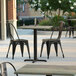 A Lancaster Table & Seating Excalibur square table top with a textured metal finish on an outdoor patio.
