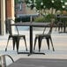 A Lancaster Table & Seating Excalibur table top with a smooth finish on a patio with chairs.
