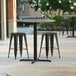 A Lancaster Table & Seating Excalibur round counter height table with a textured metal finish on an outdoor patio.