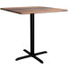 A Lancaster Table & Seating Excalibur square counter height table with a black base and a textured wooden top.
