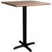 A Lancaster Table & Seating square counter height table with a black cross base and wooden top.