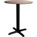 A Lancaster Table & Seating Excalibur round dining table with a wooden top and black base plate.