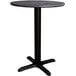 A round Lancaster Table & Seating dining height table with a black metal cross base.