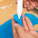 A person using a blue Ateco plastic rolling pin on a white countertop.
