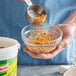 A person using a measuring spoon to pour Knorr Shrimp Bouillon into a bowl.