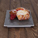 A pastry on a black textured melamine platter with raspberries.