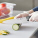 A person in gloves cutting vegetables on a cutting board with a Choice 8" Chef Knife.
