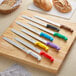 A group of knives with colorful handles on a wooden surface.