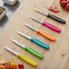 A group of Choice paring knives with colorful handles on a table.