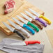 Choice chef knives with different colored handles on a cutting board.