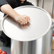 A woman using a Vollrath Wear-Ever aluminum pot cover on a large pot.