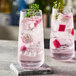 Two Nude Mirage highball glasses filled with pink drinks, ice, and a sprig of thyme.