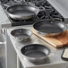 Vigor SS1 Series stainless steel non-stick fry pans with aluminum-clad bottoms and dual handles on a stove top.
