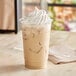 A clear EcoChoice PLA compostable plastic cup filled with iced coffee and whipped cream.