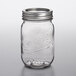 A close-up of a Kerr clear glass canning jar with a silver metal lid.