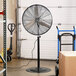 A large black TPI industrial pedestal fan on a stand.