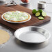A pie in a Choice aluminum pie pan on a cutting board next to a pie crust and limes.