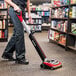 A woman using a Sanitaire cordless upright vacuum cleaner in a store.