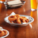 A plate of fried onion rings on a Baker's Mark pie pan on a table.